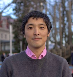 A photograph of Keita Tamura standing outside, smiling at the camera