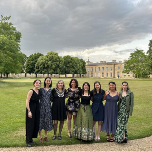 Members of the Rawlins Lab stand together as a group. They are outside in the grounds of a country estate and are smiling at the camera.